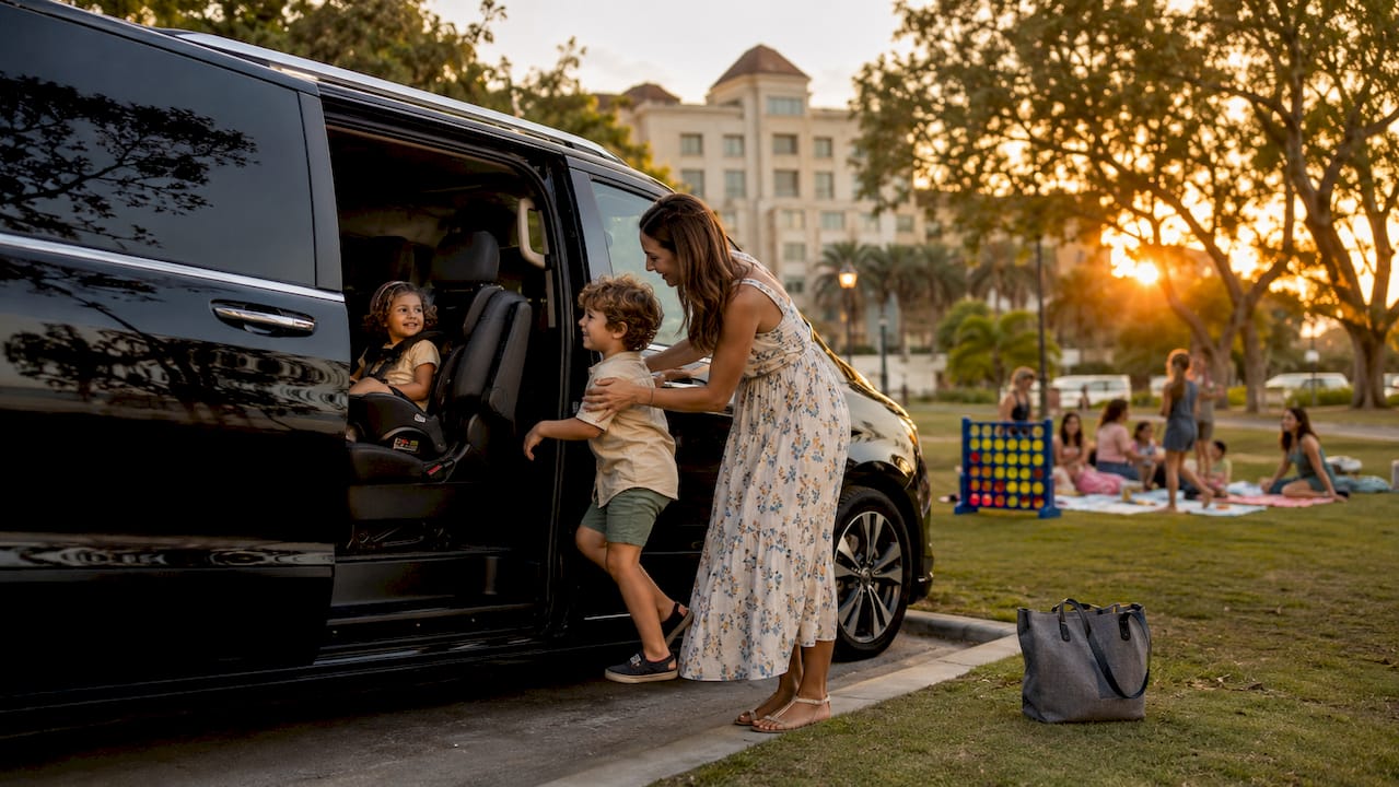 Parent buckling children inside luxury SUV at airport