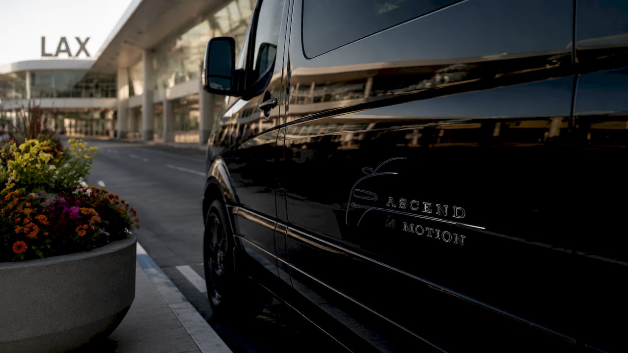 Ascend in Motion branded black Mercedes Sprinter at LAX terminal curbside