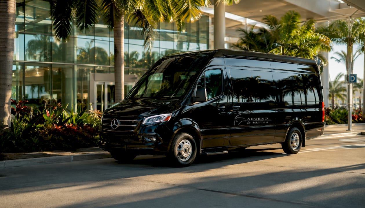 Ascend in Motion branded black luxury minivan outside airport
