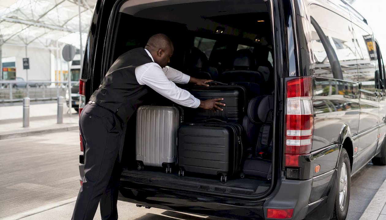 Chauffeur loading luggage and car seat into branded van