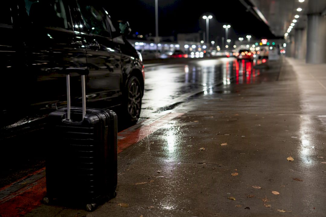 Night airport curb with vehicle silhouette and luggage