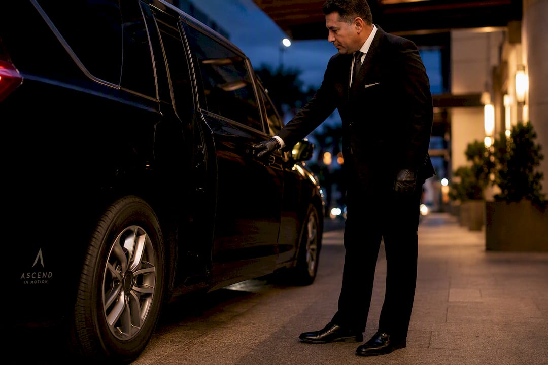 Chauffeur opening black minivan at event venue