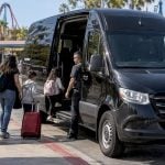 Black branded Sprinter awaiting family theme park transfer